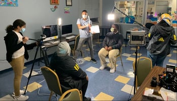 A group of enthusiastic students, armed with cameras and equipment, passionately engaged in the process of filming a program, showcasing their creativity and dedication in action.