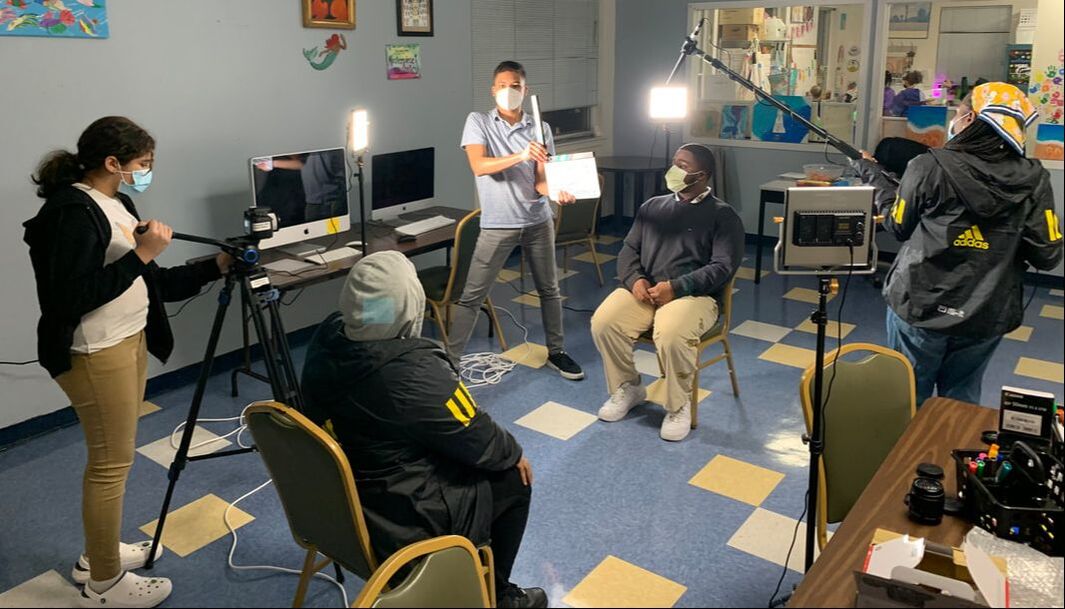 A group of enthusiastic students, armed with cameras and equipment, passionately engaged in the process of filming a program, showcasing their creativity and dedication in action.